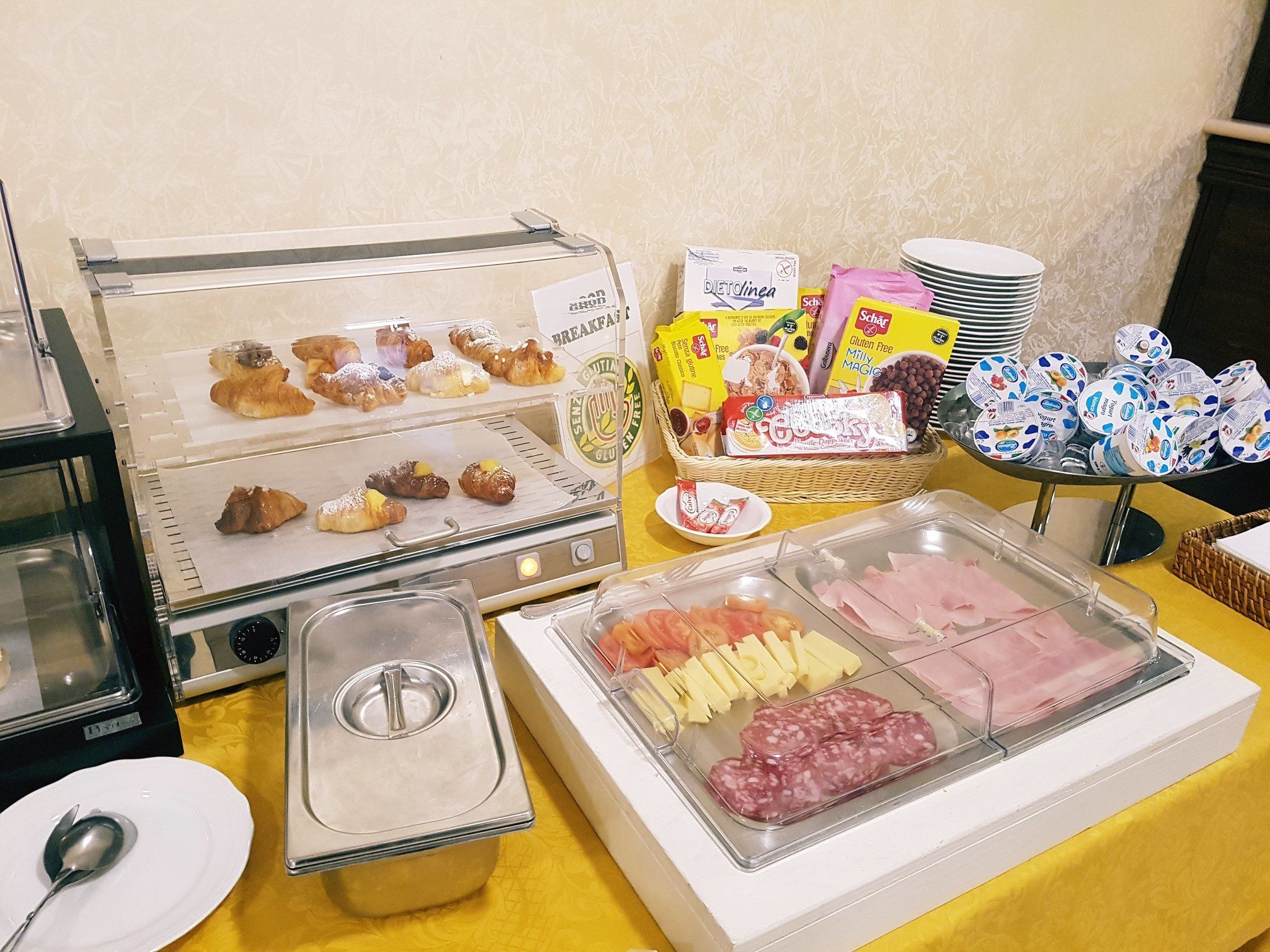 A buffet with various food items including pastries, cheese, and deli meats.