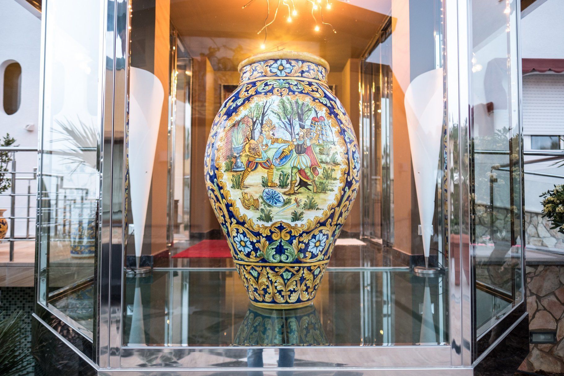 Un'ampia e decorata vasi in ceramica esposta in una teca di vetro, circondata da un edificio moderno con facciata in vetro e ringhiere in metallo.