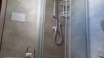 Un baño moderno con ducha envuelta en vidrio, inodoro y lavabo.