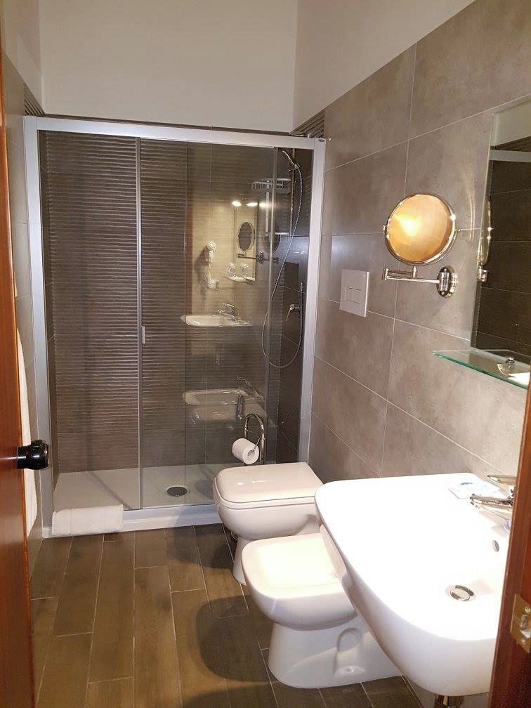 A bathroom with a glass-enclosed shower, a toilet, and a sink.