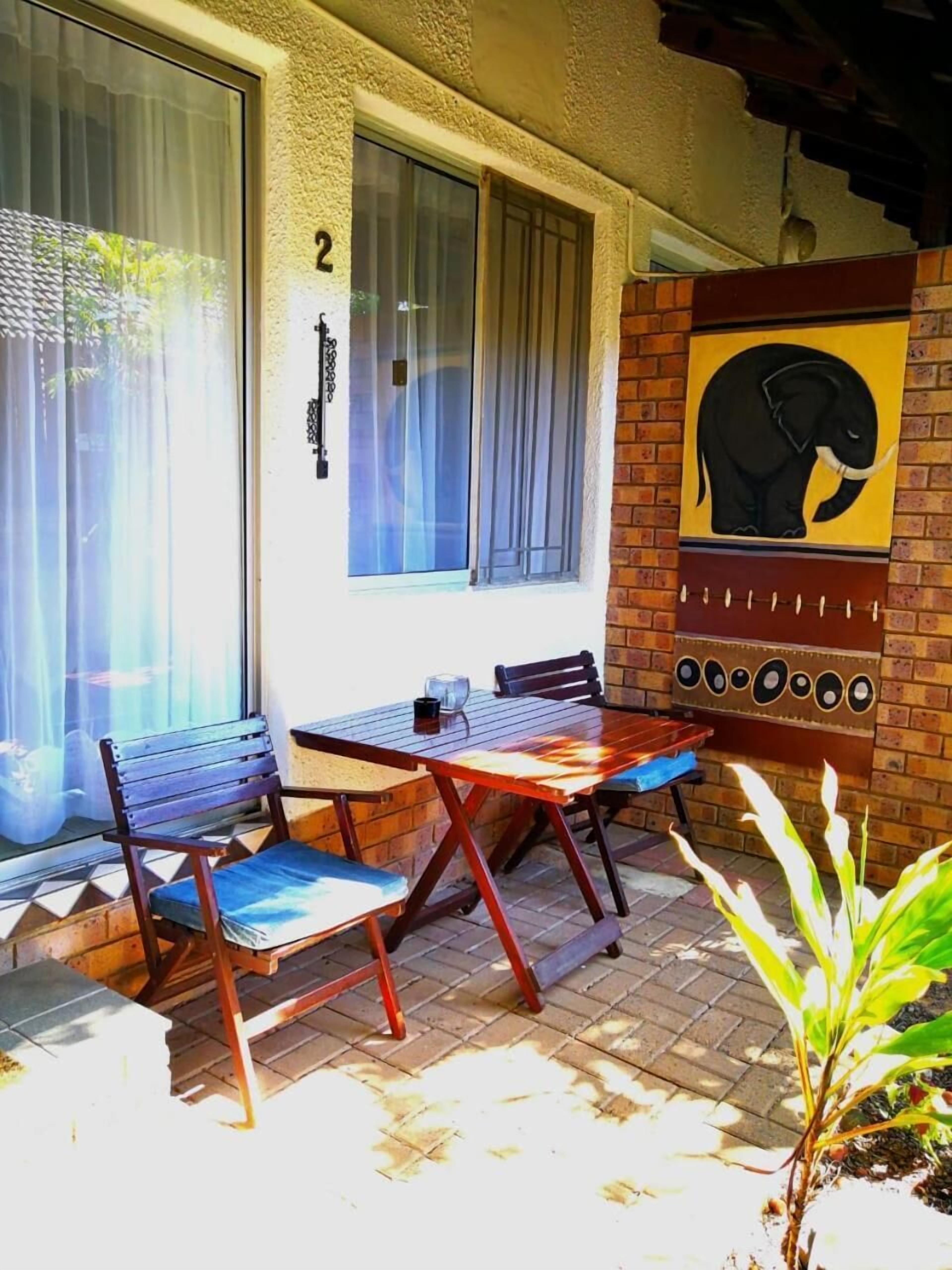 Patio esterno con tavolo e sedie, il numero '2' su una parete e un murale raffigurante un elefante.
