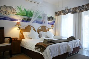 Une chambre d’hôtel comprenant un lit, une chaise, une table de chevet, une décoration murale et une fenêtre avec des rideaux.