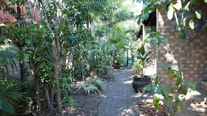 A garden pathway with a brick wall on one side and a brick building on the other. - Bhangazi Lodge (St. Lucia)