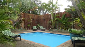 Relax by the pool surrounded by lush tropical plants and palm trees.