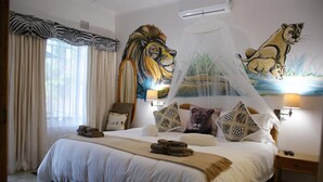 A hotel room with a large bed, a canopy, and two lion paintings on the walls. - Bhangazi Lodge (St. Lucia)
