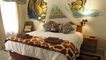 A bedroom with a bed, a lion mural, a zebra curtain, and a nightstand with a lamp.