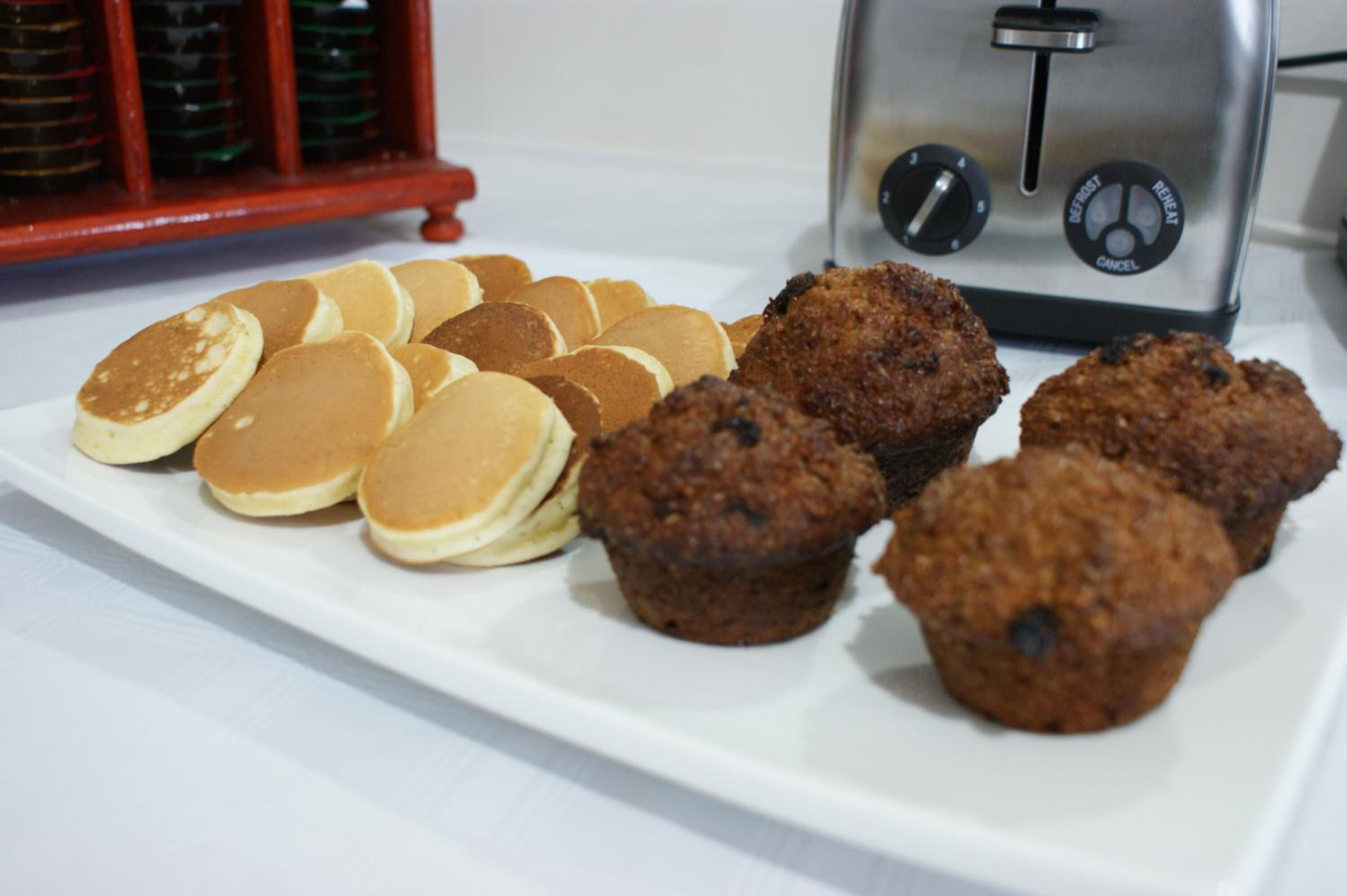 Een wit bord met pannenkoeken en muffins.