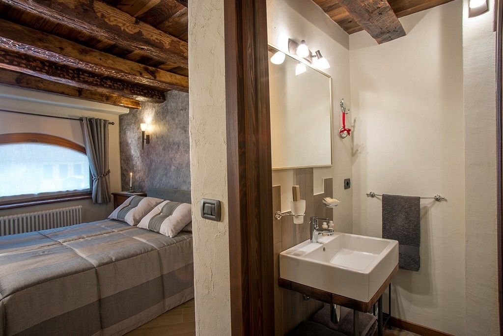 A bedroom with a bed, bedside table, and a window with curtains.