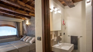 A bedroom with a bed, bedside table, and a window with curtains. - La cor de Jeremie (Montjovet)