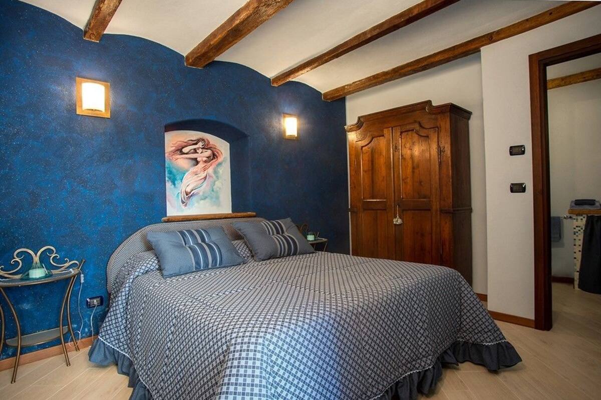 Un dormitorio con una cama grande, un armario de madera y un cuadro en la pared.