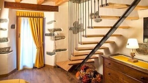 A room with a wooden ceiling, a staircase with a metal railing, a bed with a yellow bedspread, a dresser, and a basket of flowers. - La cor de Jeremie (Montjovet)