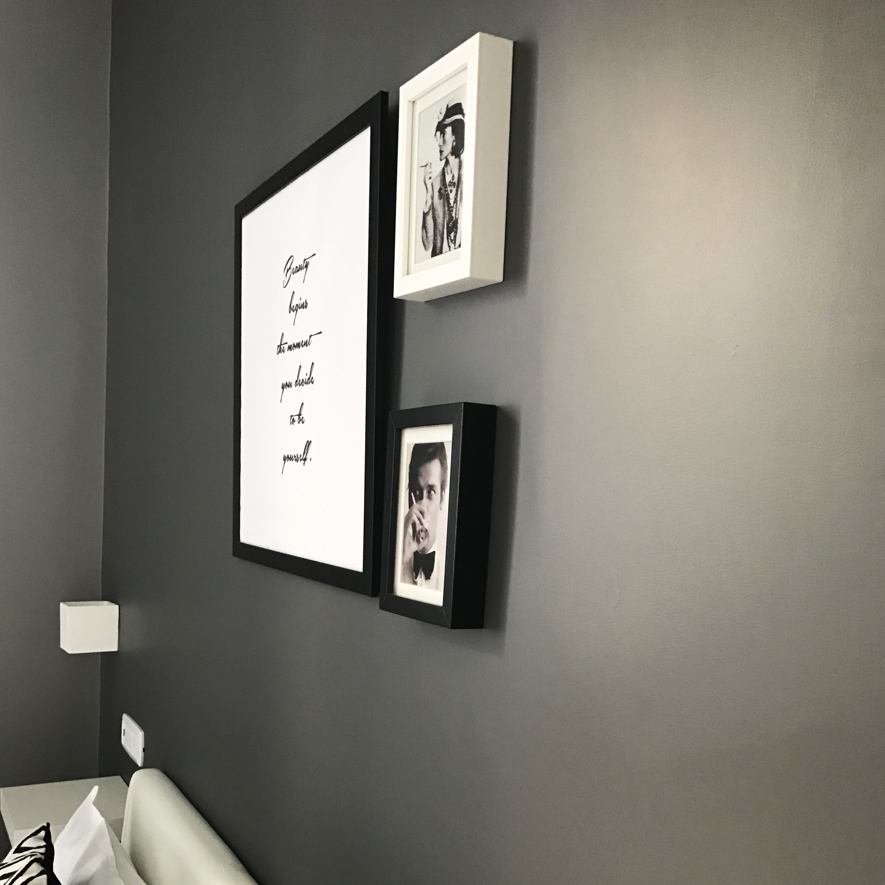 Un mur orné de trois éléments encadrés : une citation, une photographie en noir et blanc et une photographie plus petite.