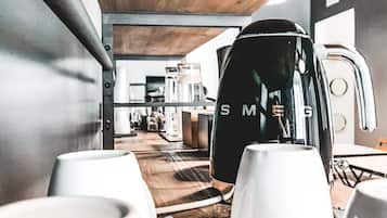 A modern kitchen with white appliances, a wooden ceiling, and a visible coffee machine.