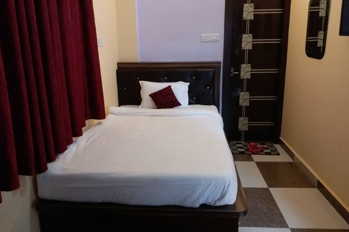 A hotel room with a bed, a door with a patterned design, and a checkered floor.