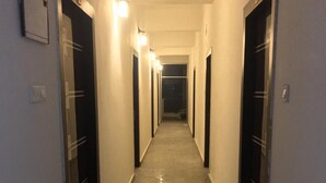 Un pasillo largo y estrecho con puertas a ambos lados, iluminado por luces empotradas.