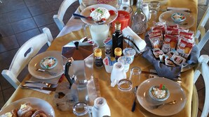 A table set for breakfast with various dishes, including croissants, a salad, and a fruit plate. - La Fattoria dei Nonni Resort dell'Etna (Paterno)