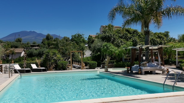 A pool with lounge chairs, a pergola, and a view of a mountain. - La Fattoria dei Nonni Resort dell'Etna (Paterno)