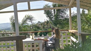 A covered outdoor seating area with a wooden deck and a white fence. - La Fattoria dei Nonni Resort dell'Etna (Paterno)