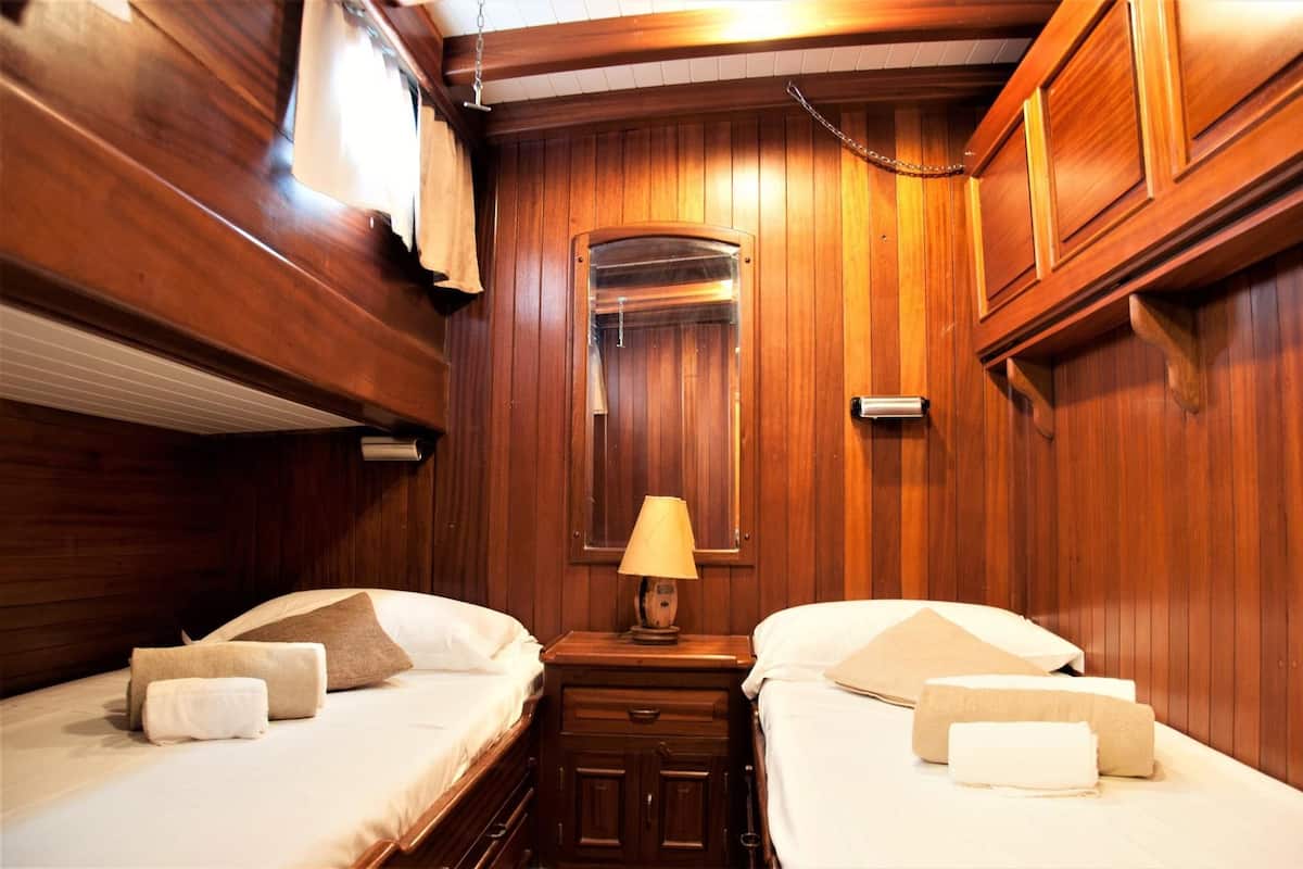 A wooden-paneled room with two beds, each with a pillow and a rolled towel.