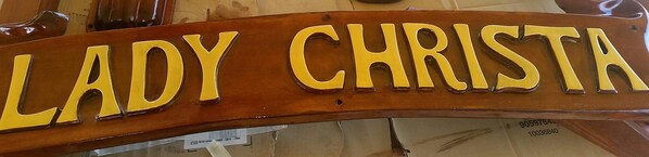 Une enseigne en bois portant le nom « LADY CHRISTA » en lettres dorées.