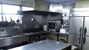 A commercial kitchen with stainless steel appliances, including a stove, oven, and refrigerator. - Rental Lodge WHITE RABBIT Madarao kogen Cottage MIDORINO KAZE (Iiyama)