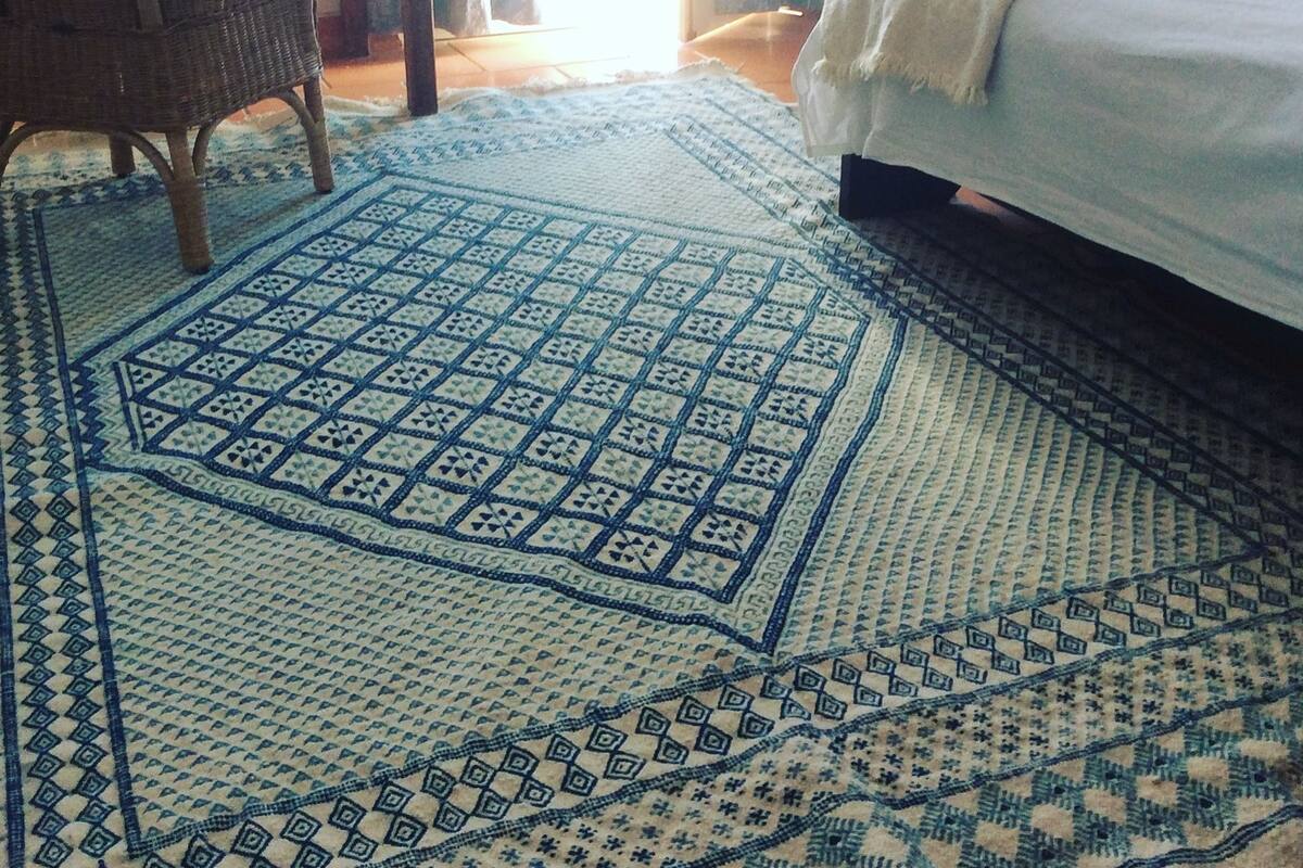 A room with a bed, a chair, and a patterned rug.