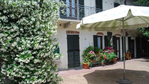 A courtyard with a potted plant, a bench, and an umbrella. - La Curandera (Rosta)