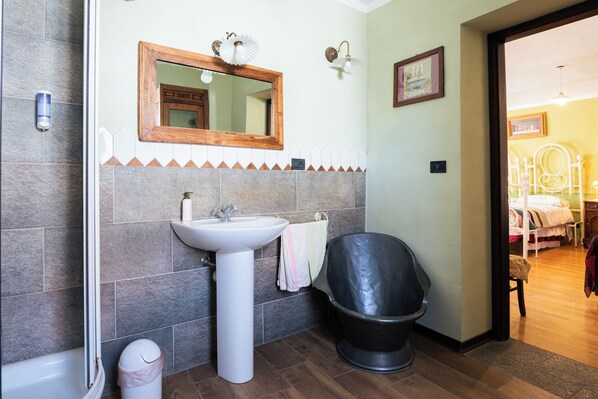 A bathroom with a sink, mirror, and black trash bin.