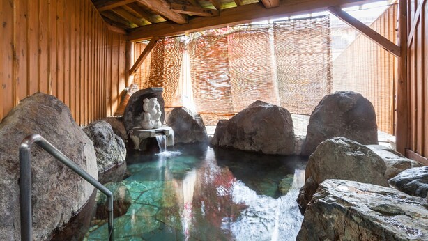 A traditional hot spring bath with large rocks and a wooden structure. - Condominium Hotel Naeba West (Yuzawa)