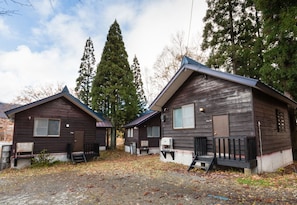 Cabins feature pitched roofs and front porches with railings, set amidst a natural backdrop.