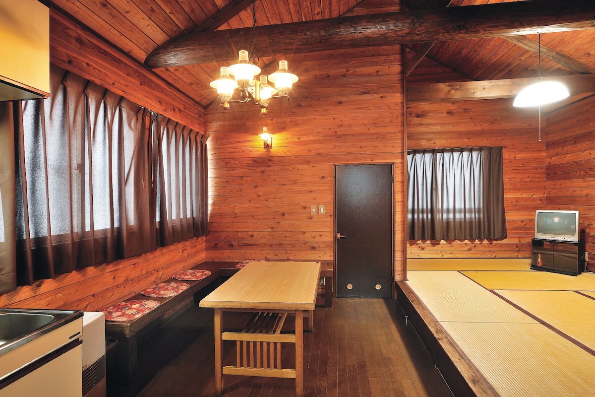 Traditional Japanese-style room with tatami flooring, wooden paneling, and a small television.
