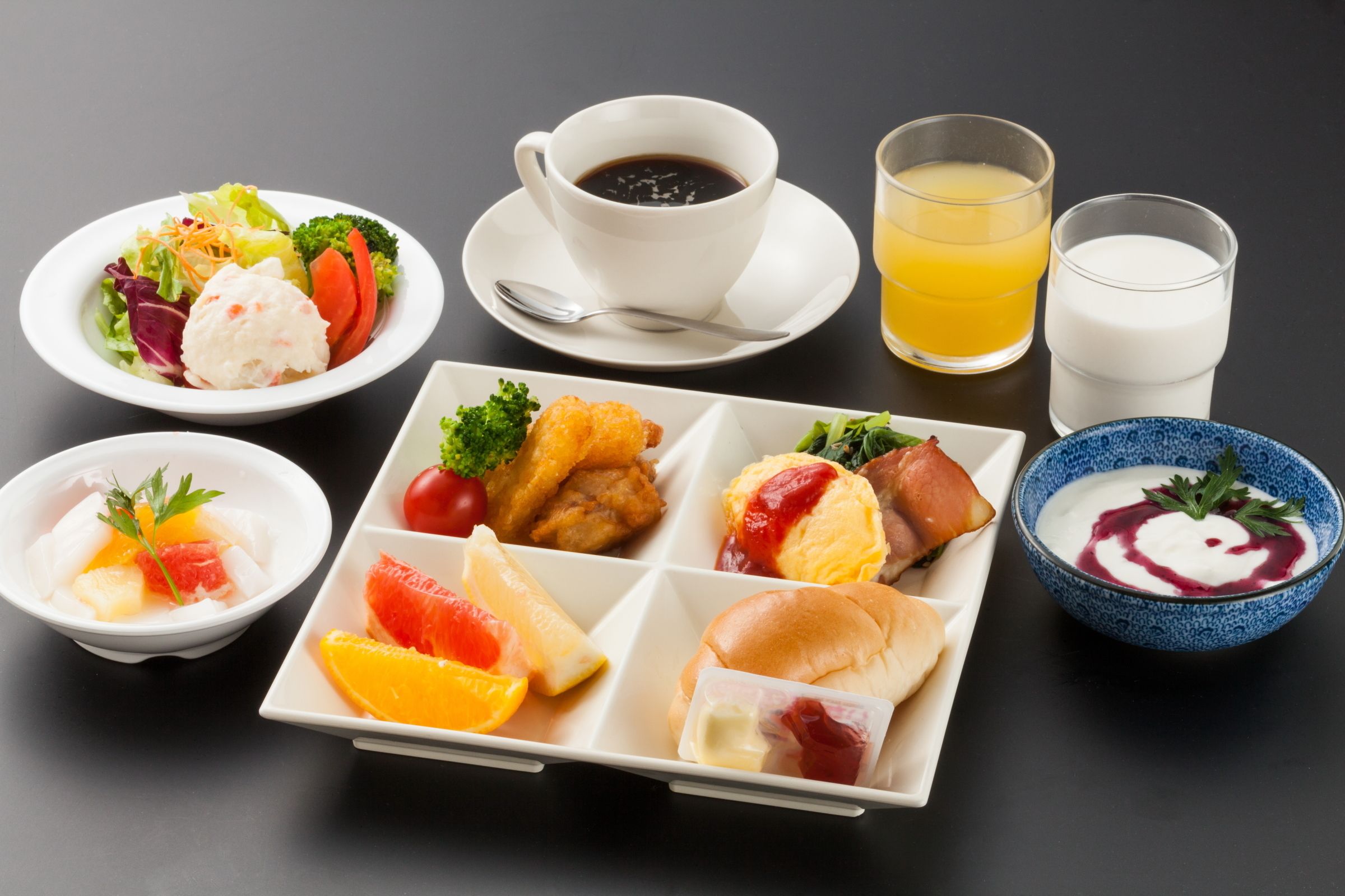 A variety of food items including a salad, soup, and sandwiches, along with cups of coffee and juice.