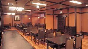 A restaurant with multiple tables and chairs, wooden flooring, and a tiled floor leading to the entrance. - Condominium Hotel Naeba West (Yuzawa)