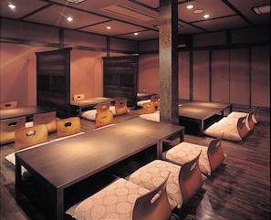 Relax in a stylish room with a long table and comfortable chairs, surrounded by dark panelled walls and recessed lighting.