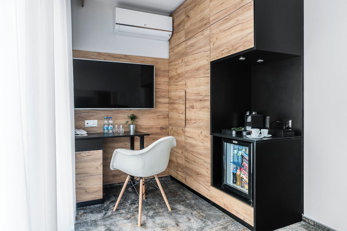 A modern kitchen with a built-in refrigerator, a microwave, and a coffee machine. There is a wooden accent wall and a large window above the counter.