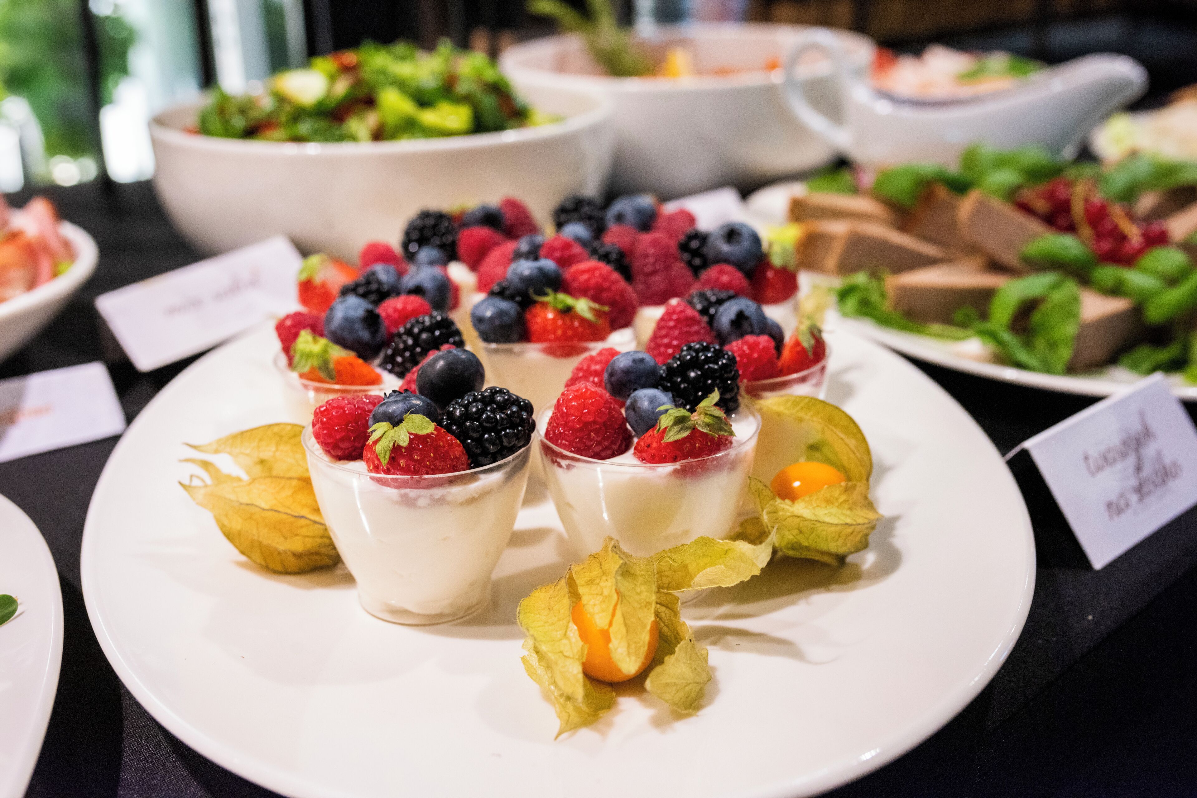Exhibición de postres con dulces cubiertos de fruta sobre platos blancos.
