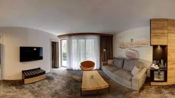 Uma sala de estar moderna com televisão de tela plana, mesa de centro de madeira, sofá e um pequeno canto de estar com uma tigela.