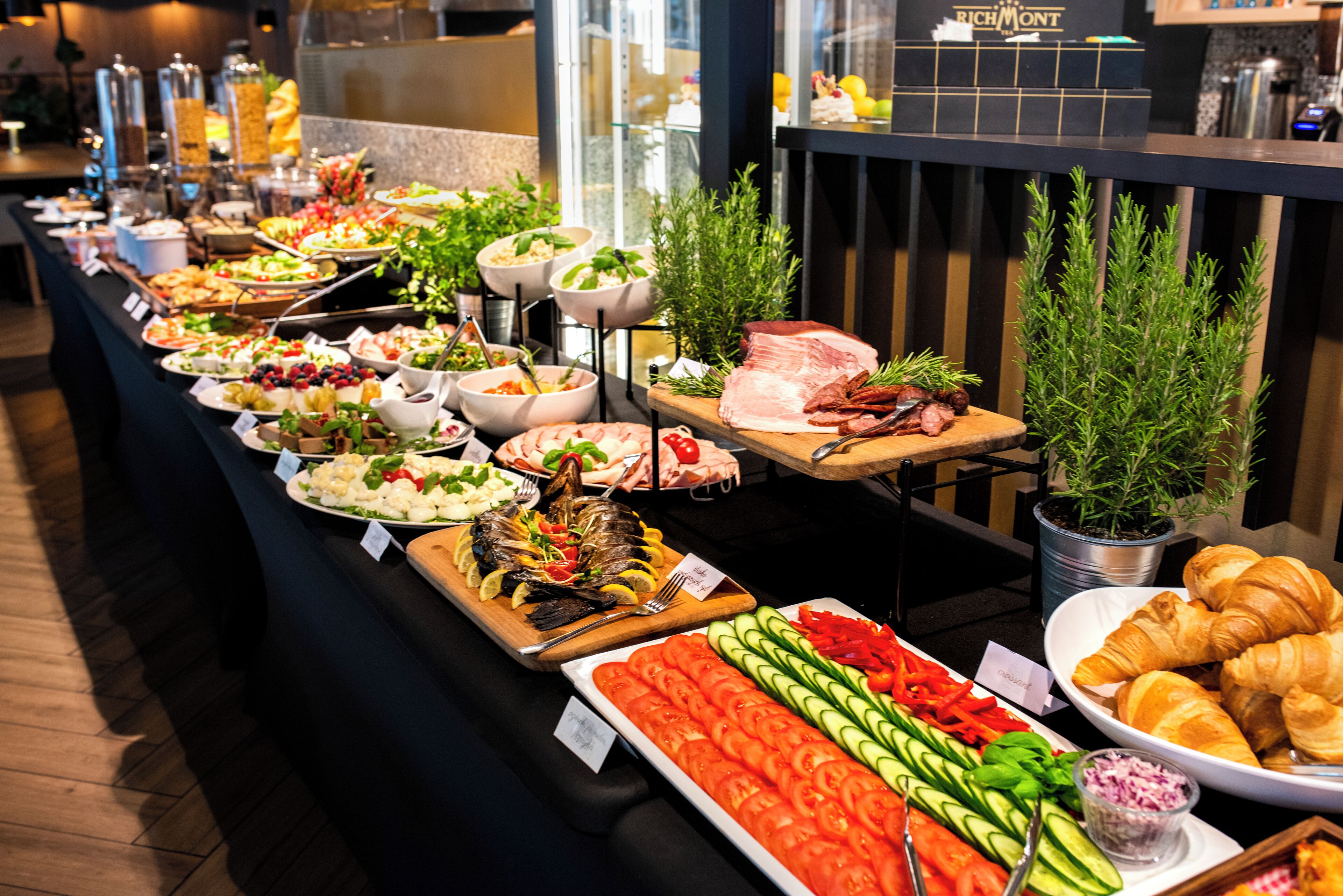 Un buffet proposant une variété de plats, notamment des fruits, des légumes, de la viande et des pâtisseries.