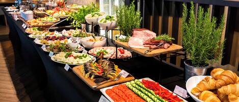A buffet with various food options including fruits, vegetables, meats, and pastries.