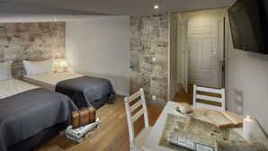 A hotel room with two beds, a small table with a book and a candle, a wooden wall, and a television mounted on the wall. - Loft Piotrkowska by Good Time (Lodz)