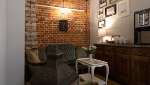 A cozy living room with a brick wall, a green sofa, a white table, and a coffee machine. - Loft Piotrkowska by Good Time (Lodz)