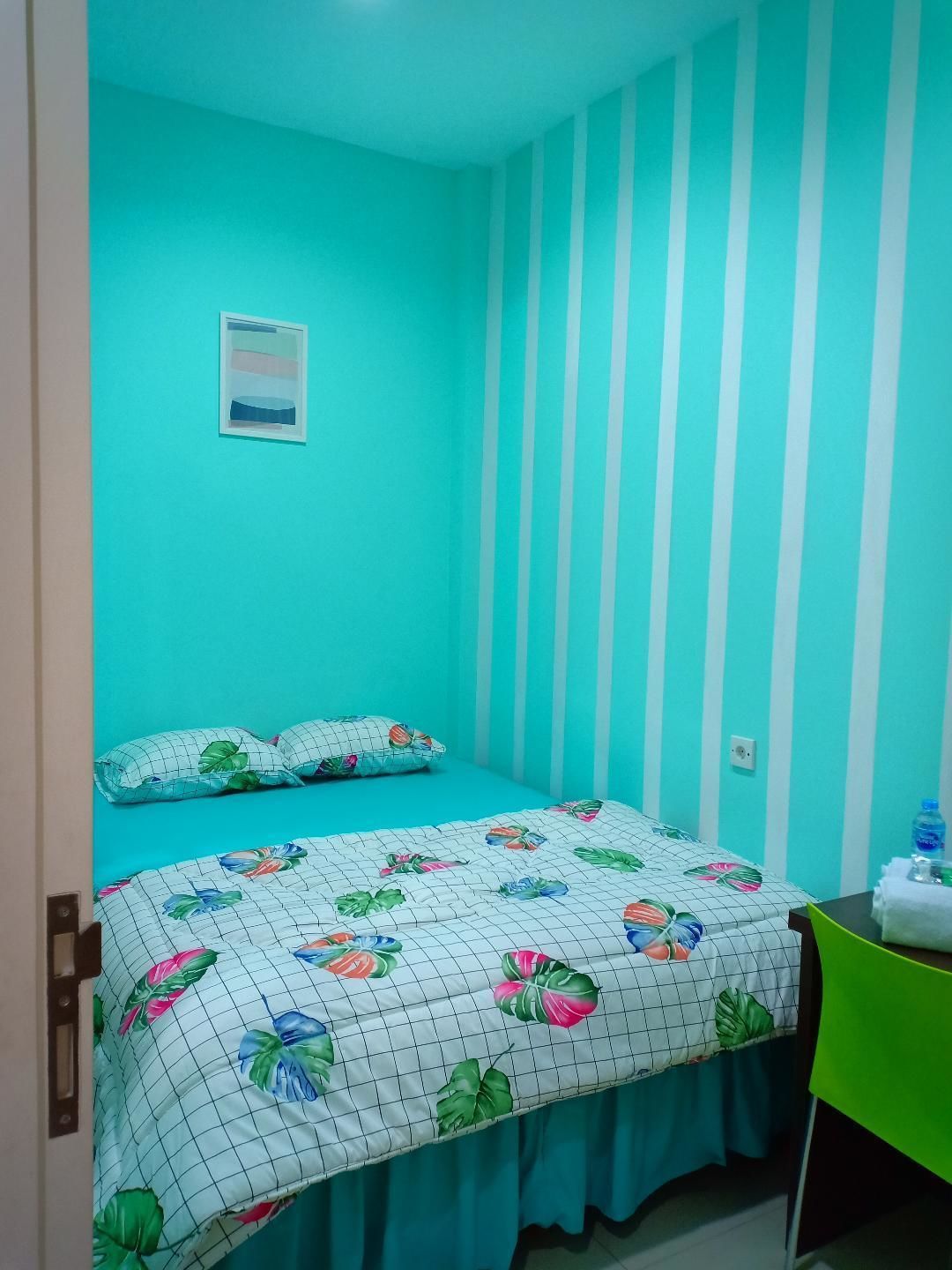 Een kamer met een bed, een stoel en een wand met verticale strepen.