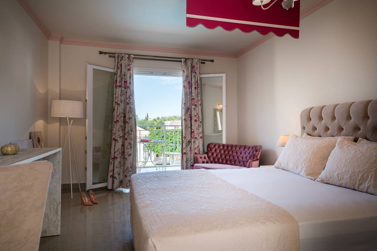 Una camera da letto con un letto grande, una sedia, una scrivania e vista sull'esterno.
