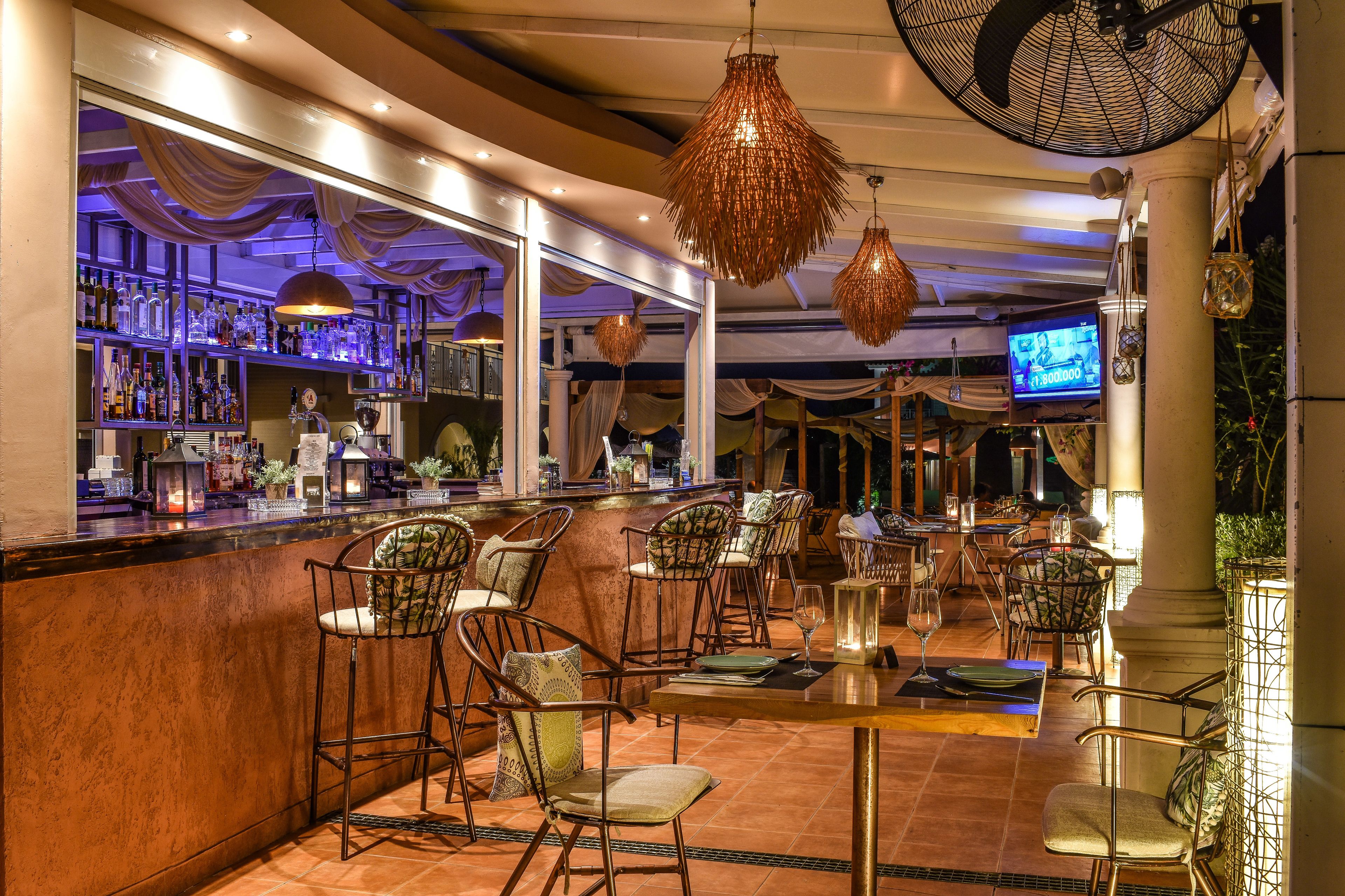 Uma área de bar com balcão, banquetes e uma tela de televisão.