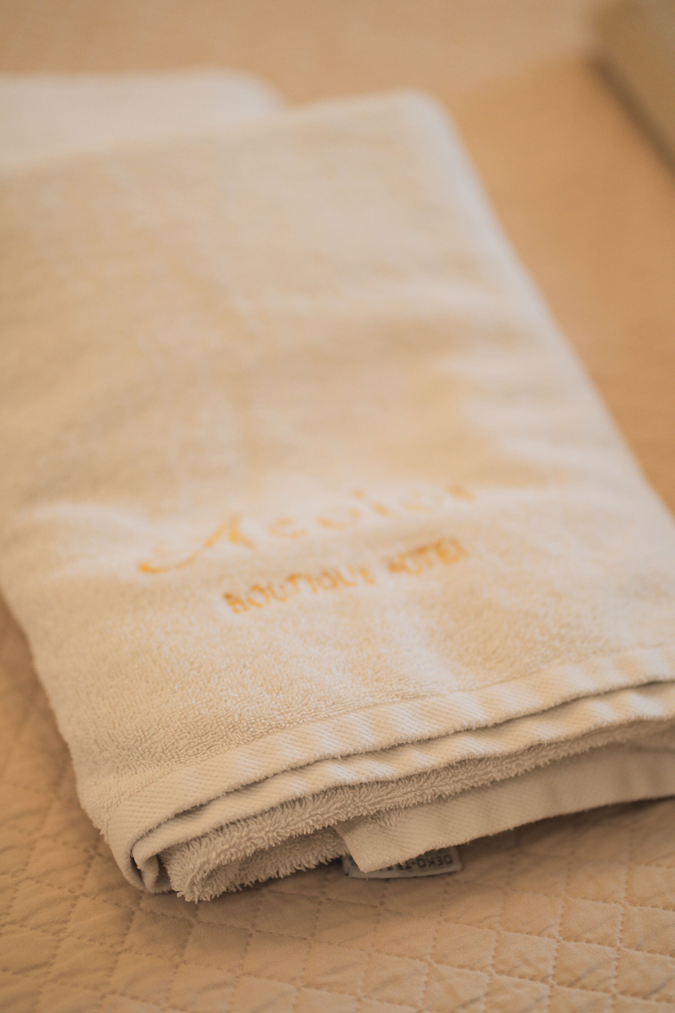 A folded white towel with a visible logo on a textured surface.