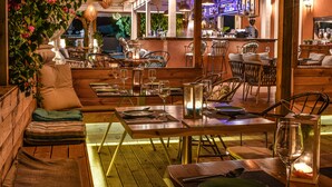Ein Restaurant mit Holztischen, gedeckten Tischen und einer Bar mit Flaschen.