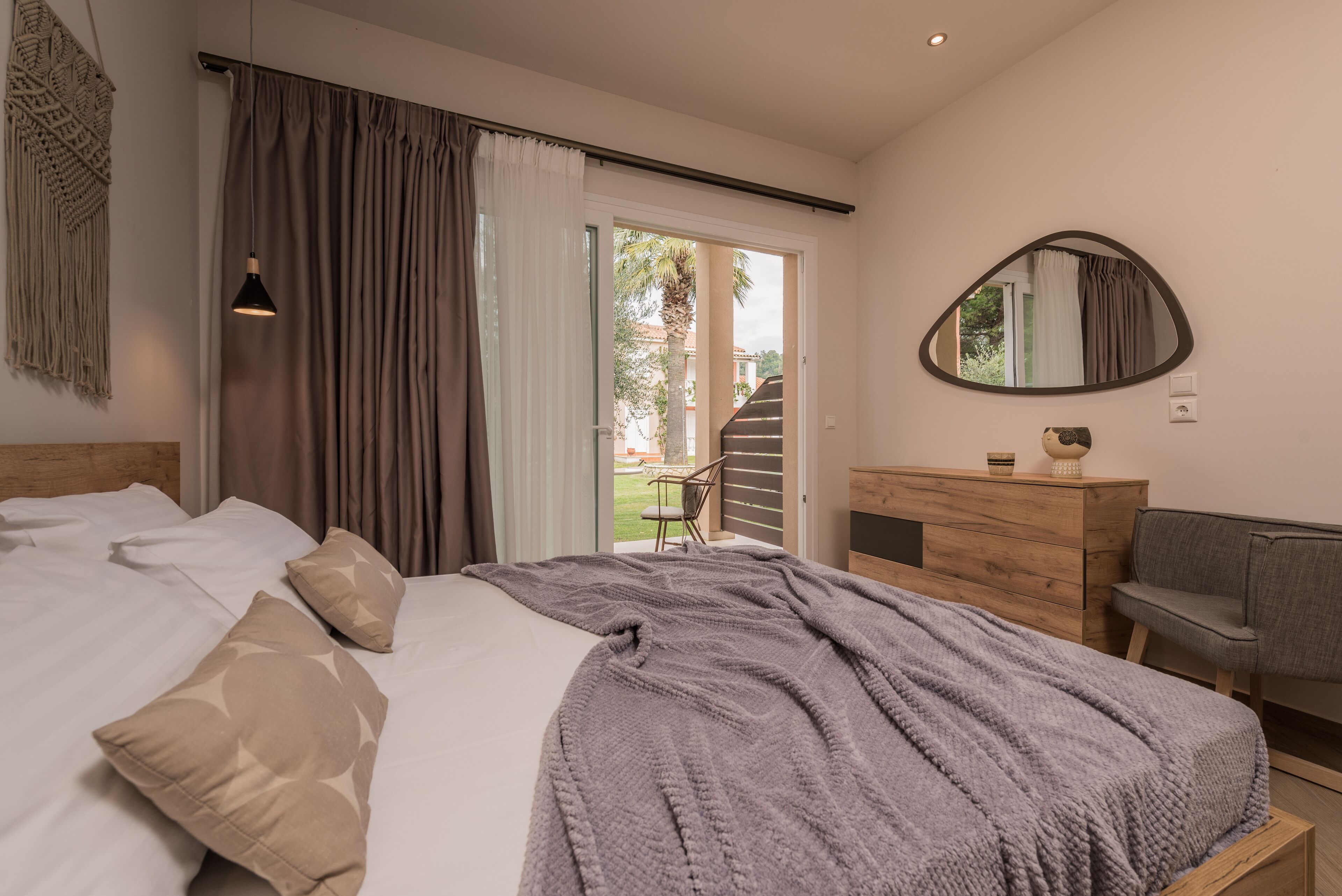 Un dormitorio con cama, cómoda, espejo y vistas al exterior.