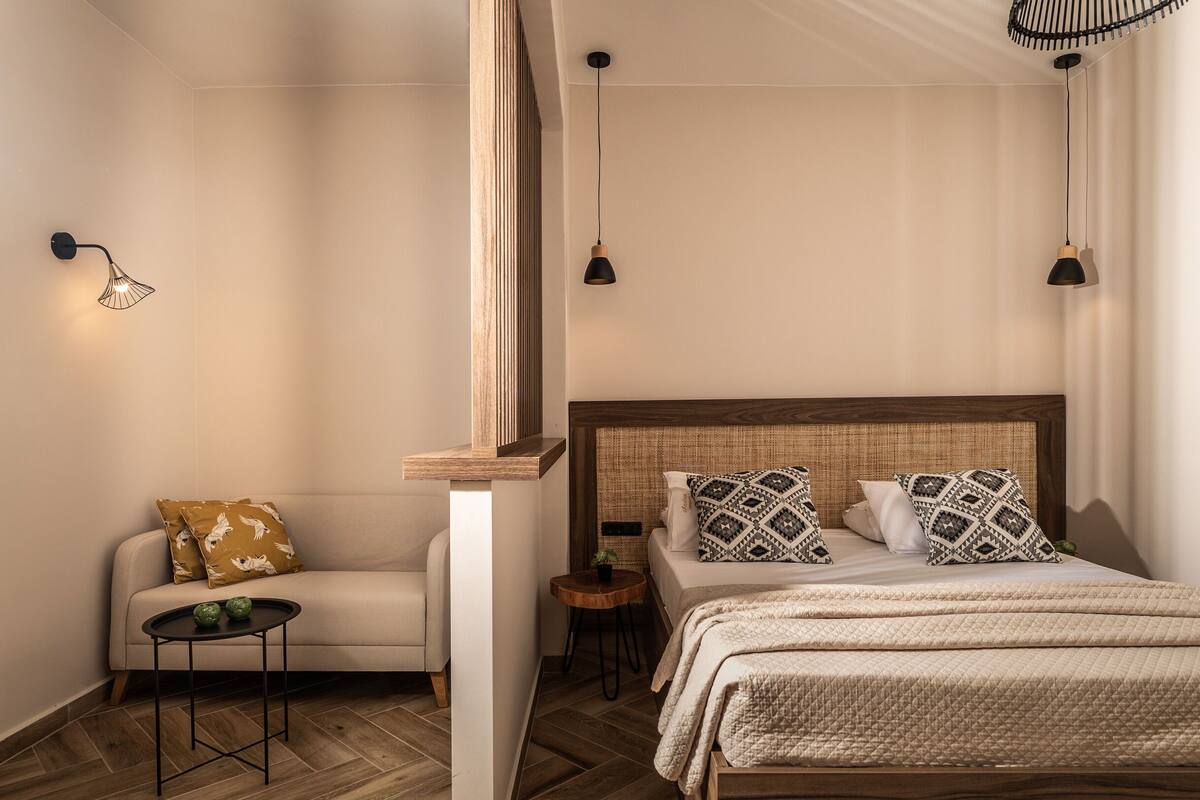 Una camera da letto con un letto, un divano, un tavolino e una lampada a parete.