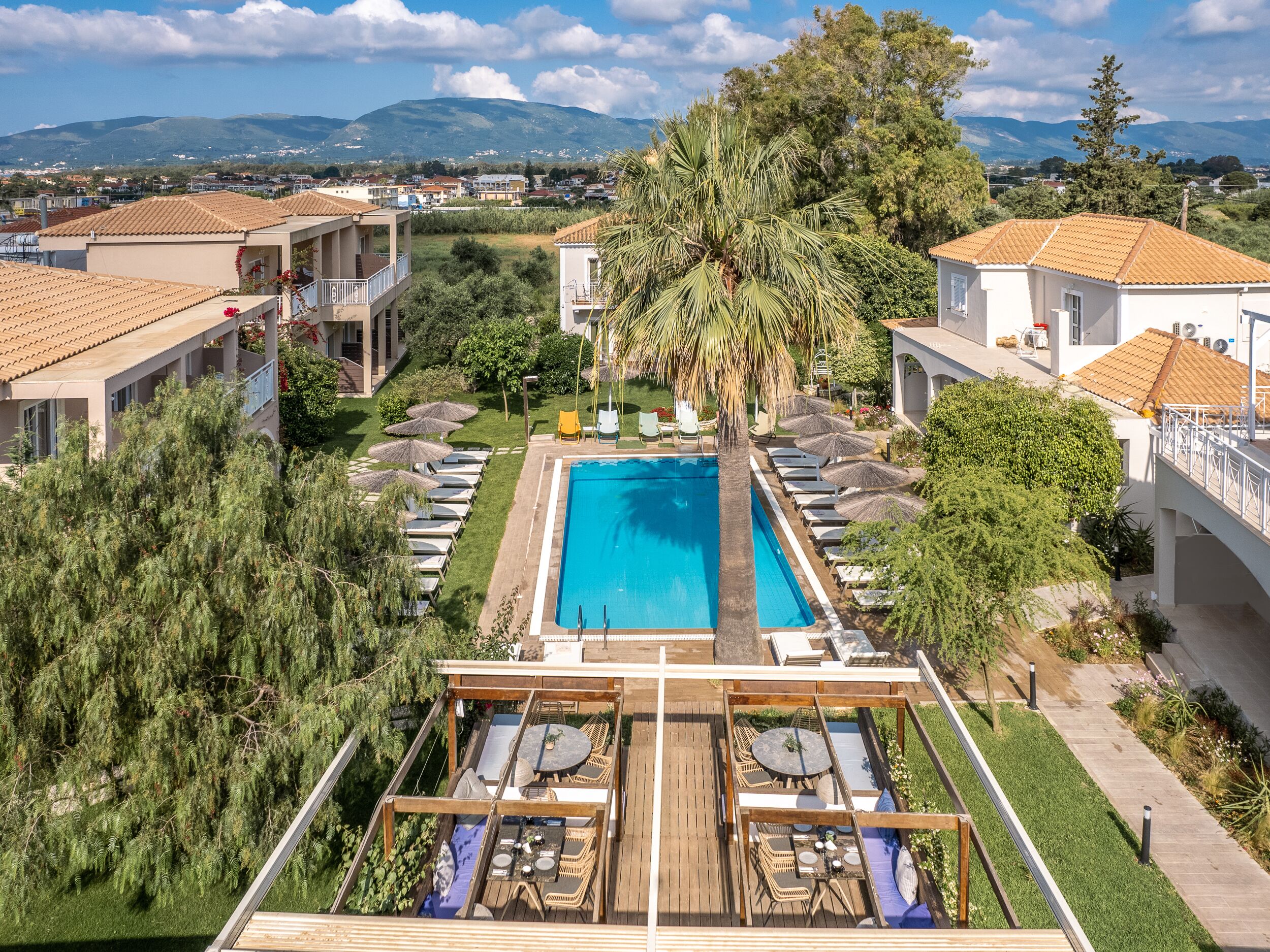 Un resort con piscina, area salotto esterna e vista sul paesaggio circostante.