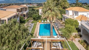 Un resort con piscina, area salotto esterna e vista sul paesaggio circostante.